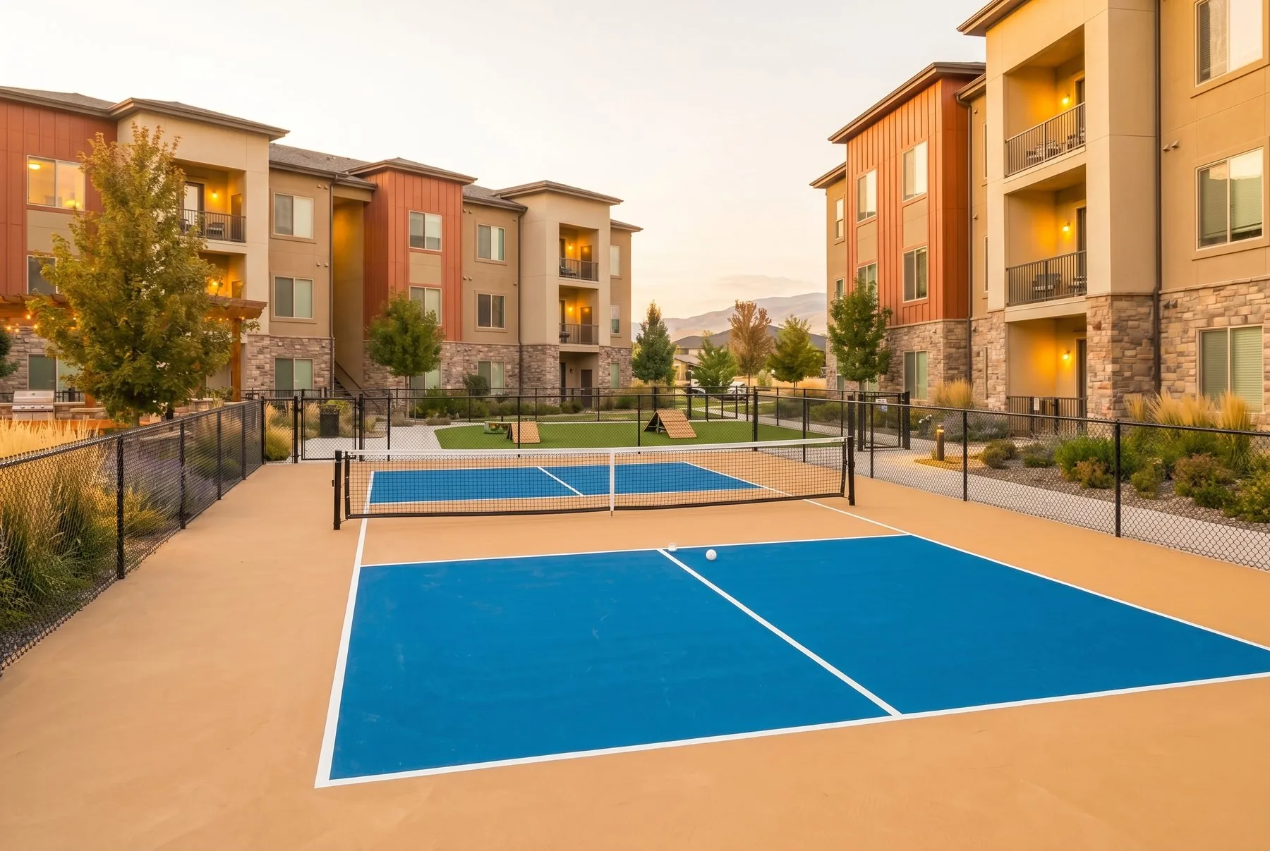 Two on-site pickleball courts at Arête Residences at golden hour, framed by warm beige apartment buildings