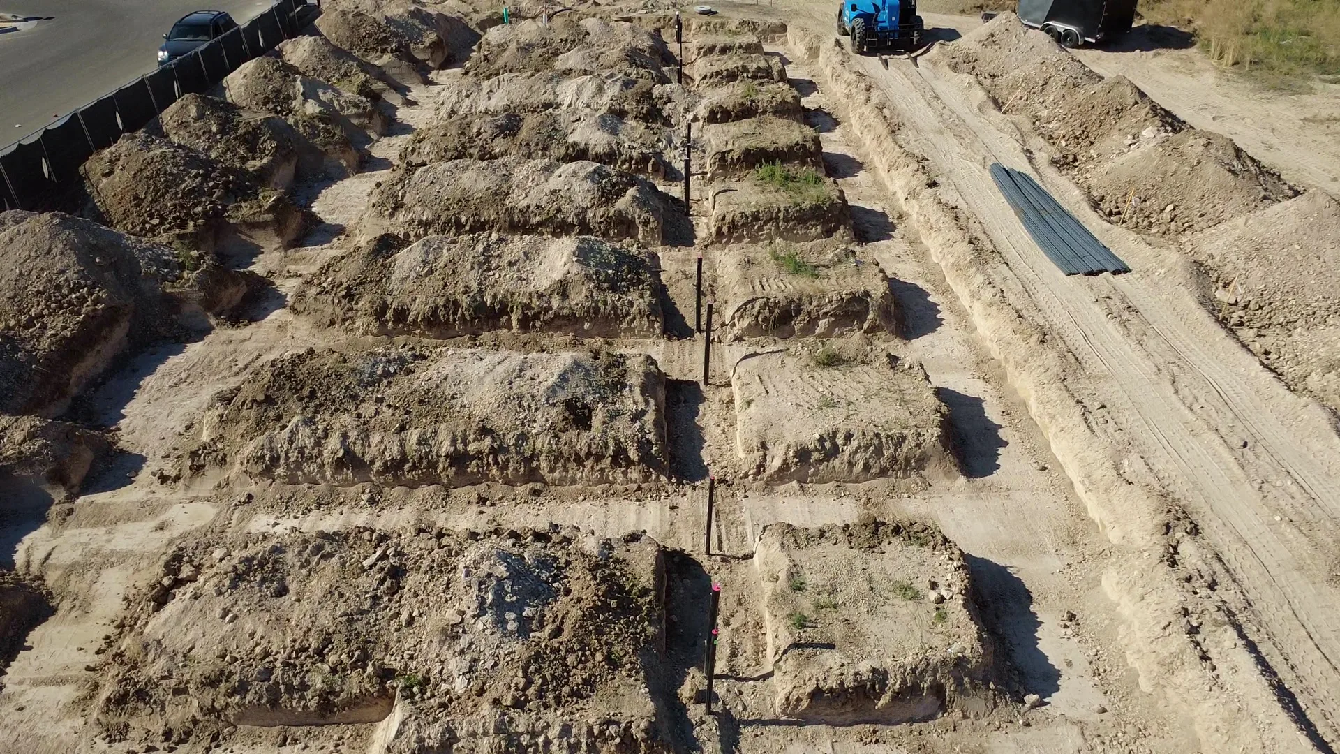 Aerial view of long rows of formed concrete footings and rebar grids for the Arête townhome foundations, with a construction crew working in the forms — July 10, 2026