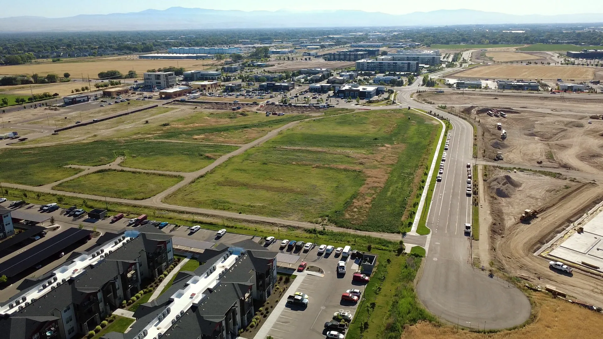 Wide aerial of the Arête site and the surrounding Southwest Meridian neighborhood, with graded pads, roadways, and the Boise foothills on the horizon — July 10, 2026