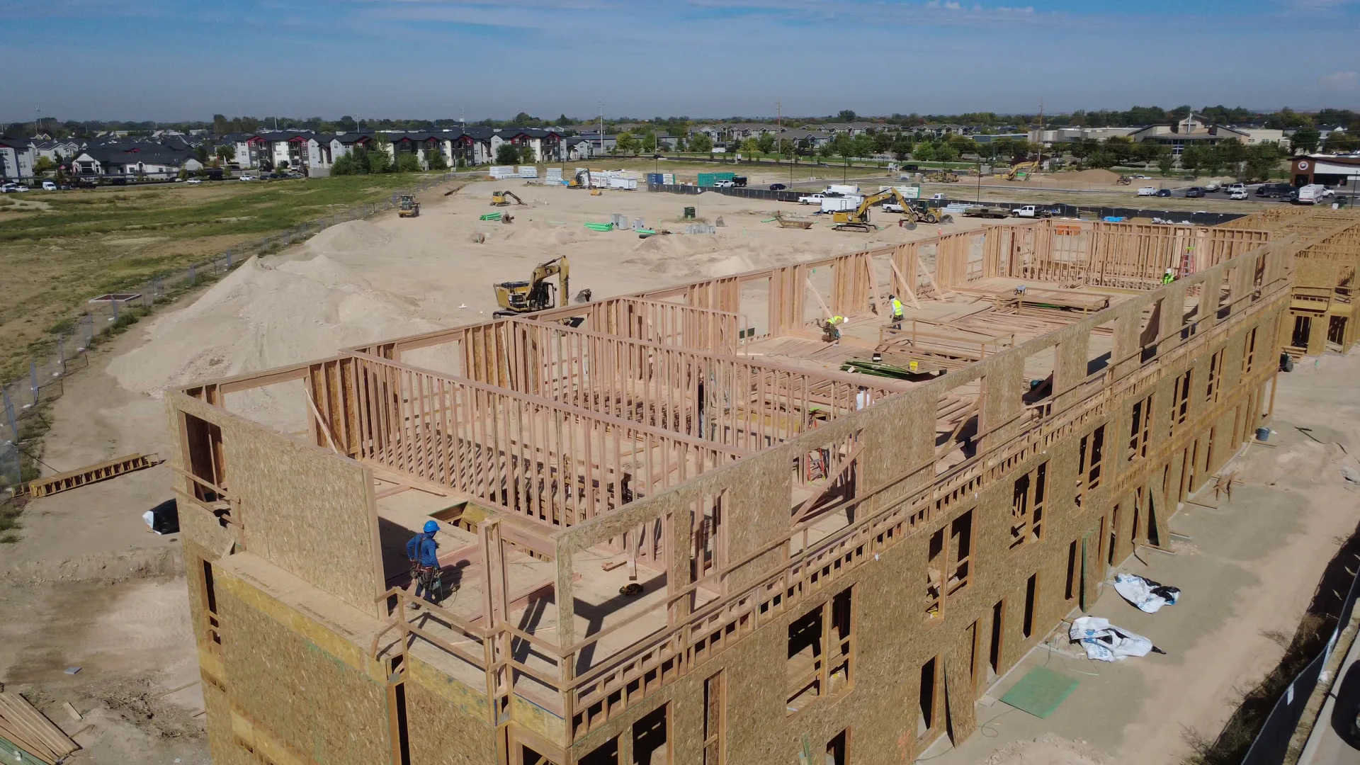 Crews framing the Arête townhomes from above in September 2026 — three-story wood framing with construction workers on site