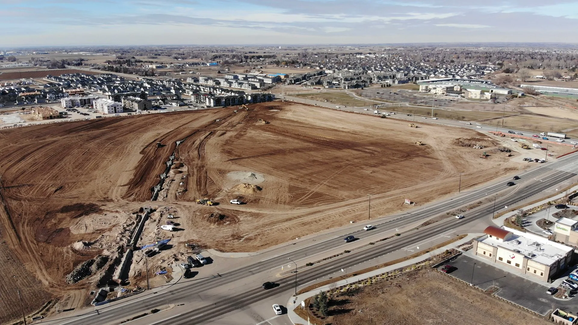 Brown dirt earthwork in progress, February 2022, with equipment tracks visible and a road being cut through the property