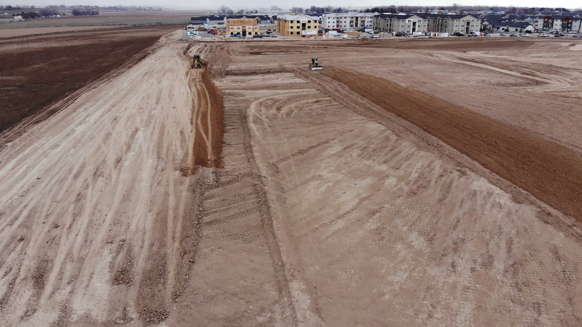 Concrete drainage and canal structures being installed in March 2022, with an excavator working on the embankment