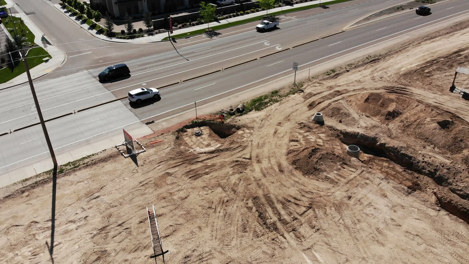 Wide aerial of the Discovery Meridian site in May 2022, showing graded earth, the main road cutting through, and surrounding farmland