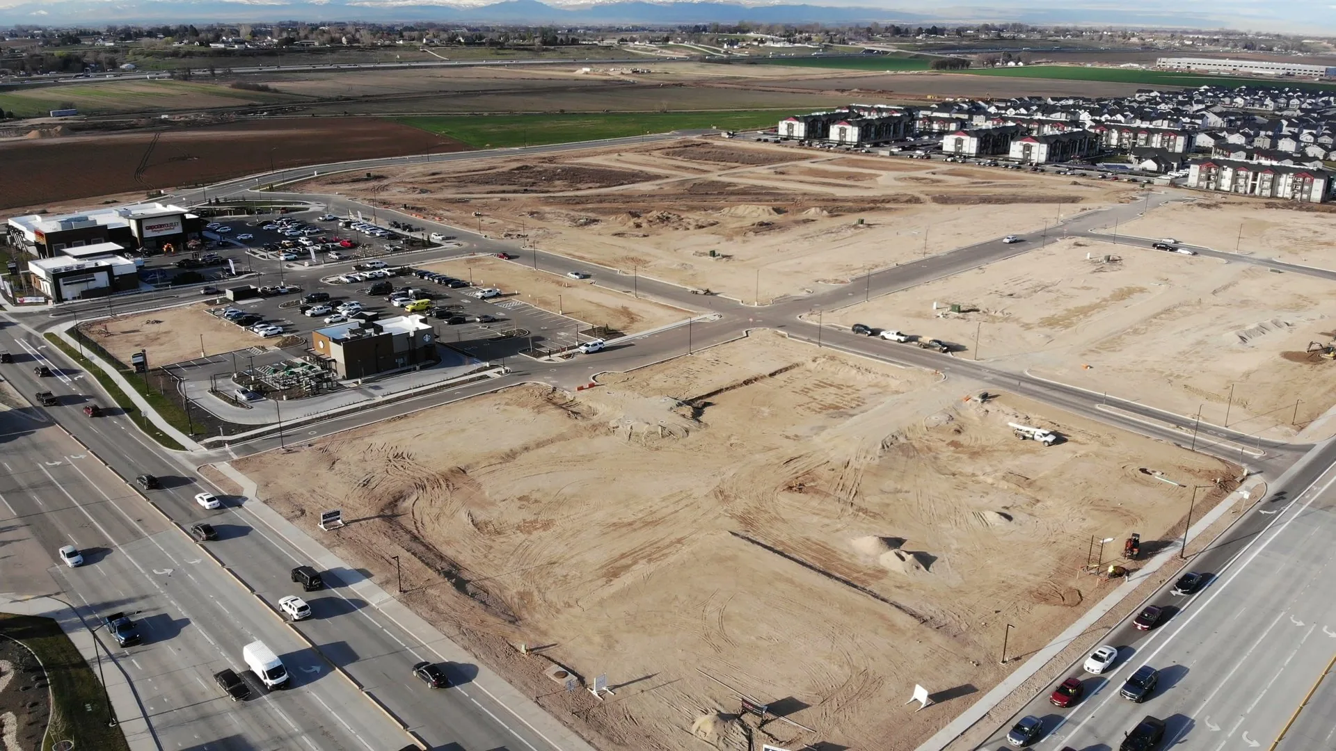Aerial of the site in March 2024 showing commercial buildings up and operating on the perimeter pads, with residential pads still bare in the foreground